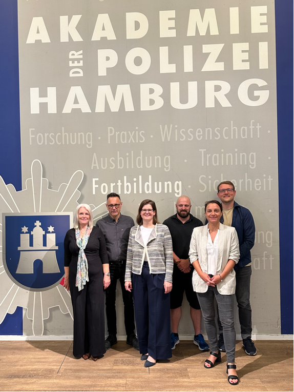 Drei Frauen und drei Männer unter dem Logo der Polizeiakademie Hamburg